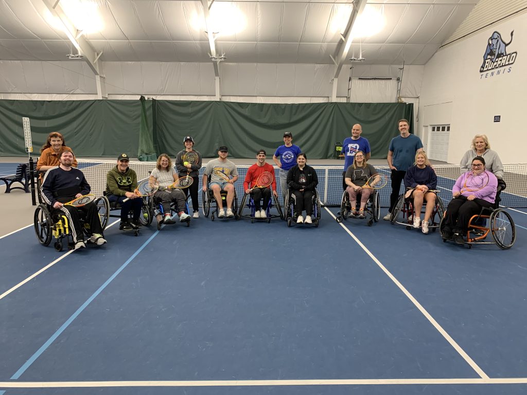 A large group of wheelchair and standing tennis players played together for a National Tennis Month event.