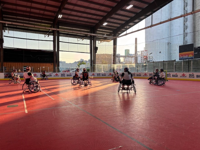 Eight wheelchair lacrosse players practicing.