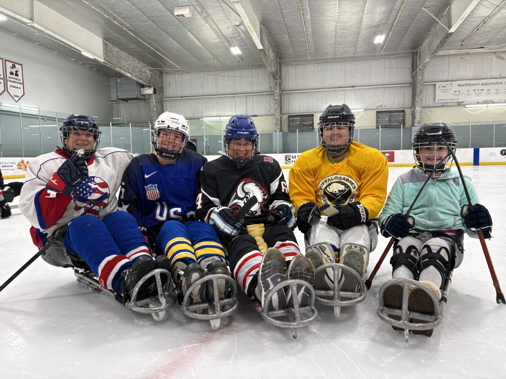 US Sled Hockey athlete Maddy Eberhard with other girls and women in hockey sleds during a clinic.
